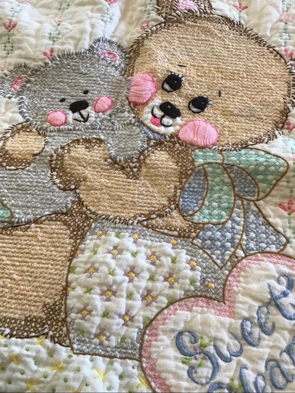 Vintage handmade baby quilt featuring embroidered teddy bears